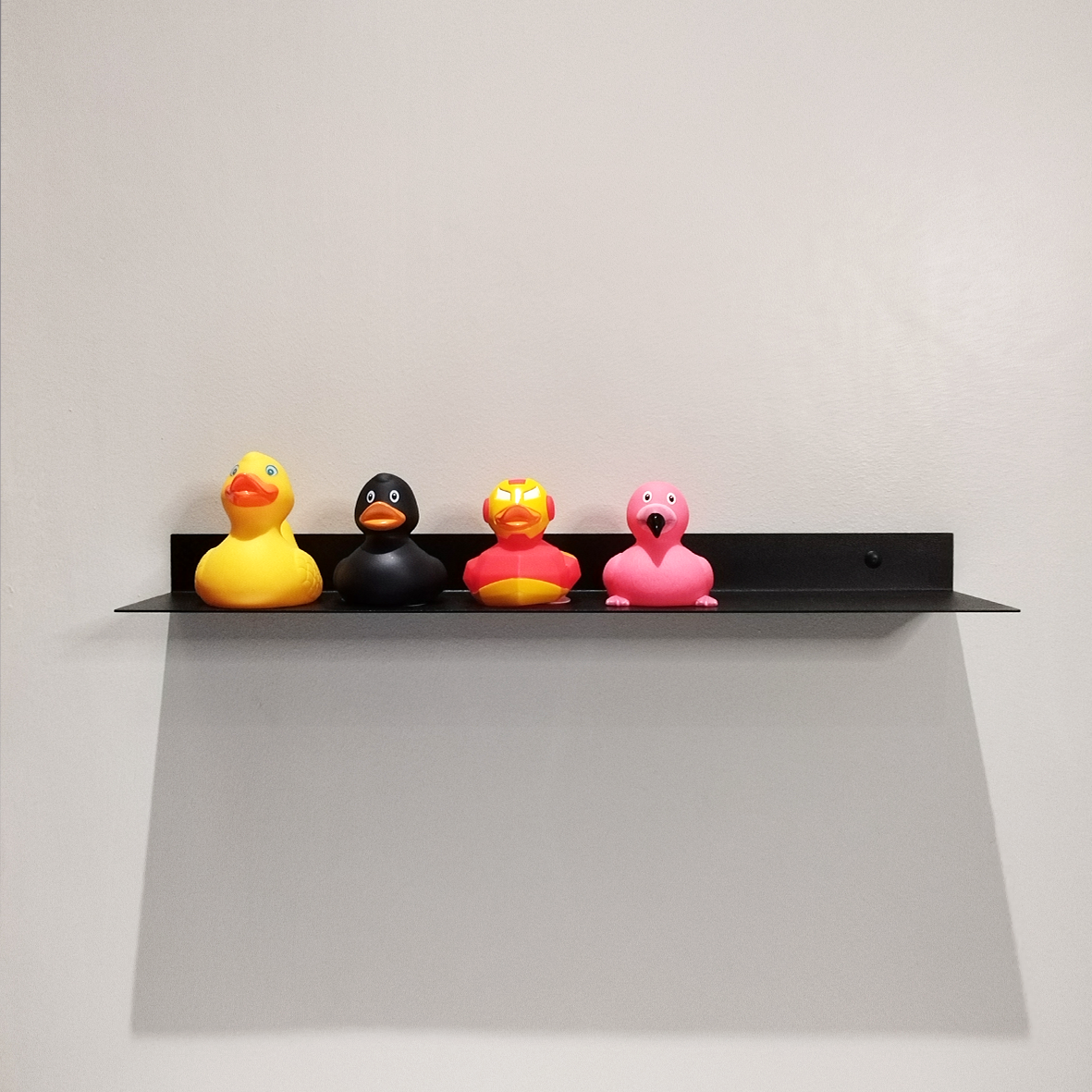 A black steel shelf in a modern bathroom design in Johannesburg. The modern bathroom shelf holds 4 rubber ducks in various colours.