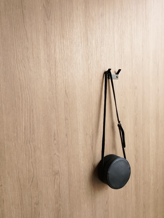 A black bathroom towel hook or a black wall hook or a handbag hook hanging a black handbag in a luxury design store in Johannesburg