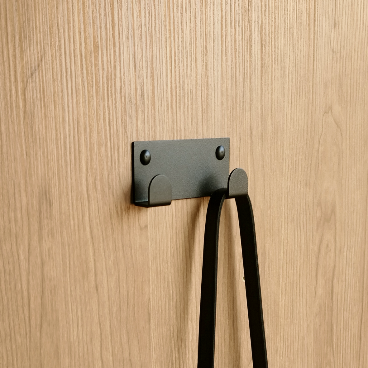 A towel hook in South Africa or a black wall hook is hanging a white bath towel in a furniture design store in South Africa