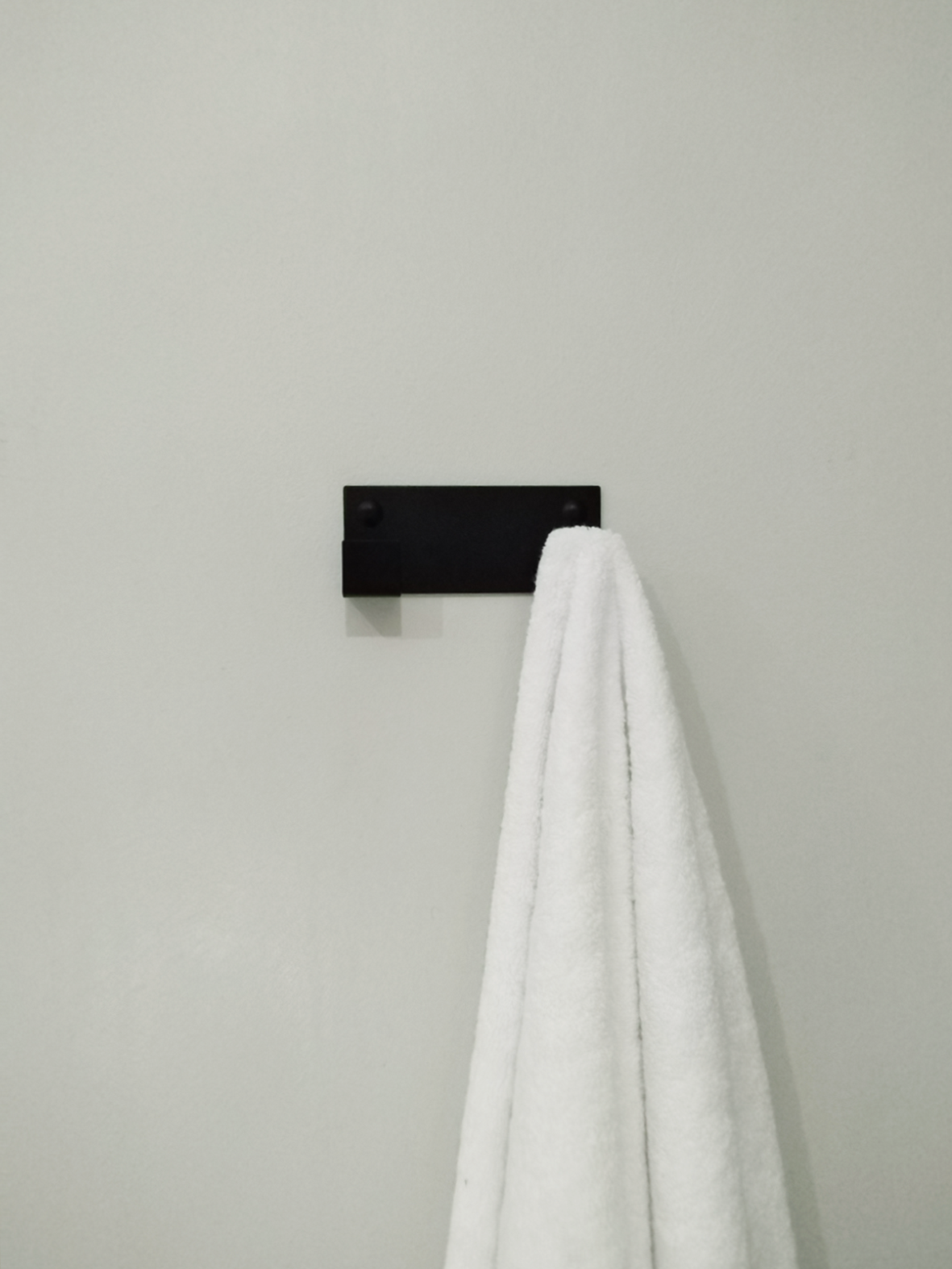 A black wall hook for hanging coats or a black towel hook is hanging a white bathrobe in a bathroom design store in Johannesburg 