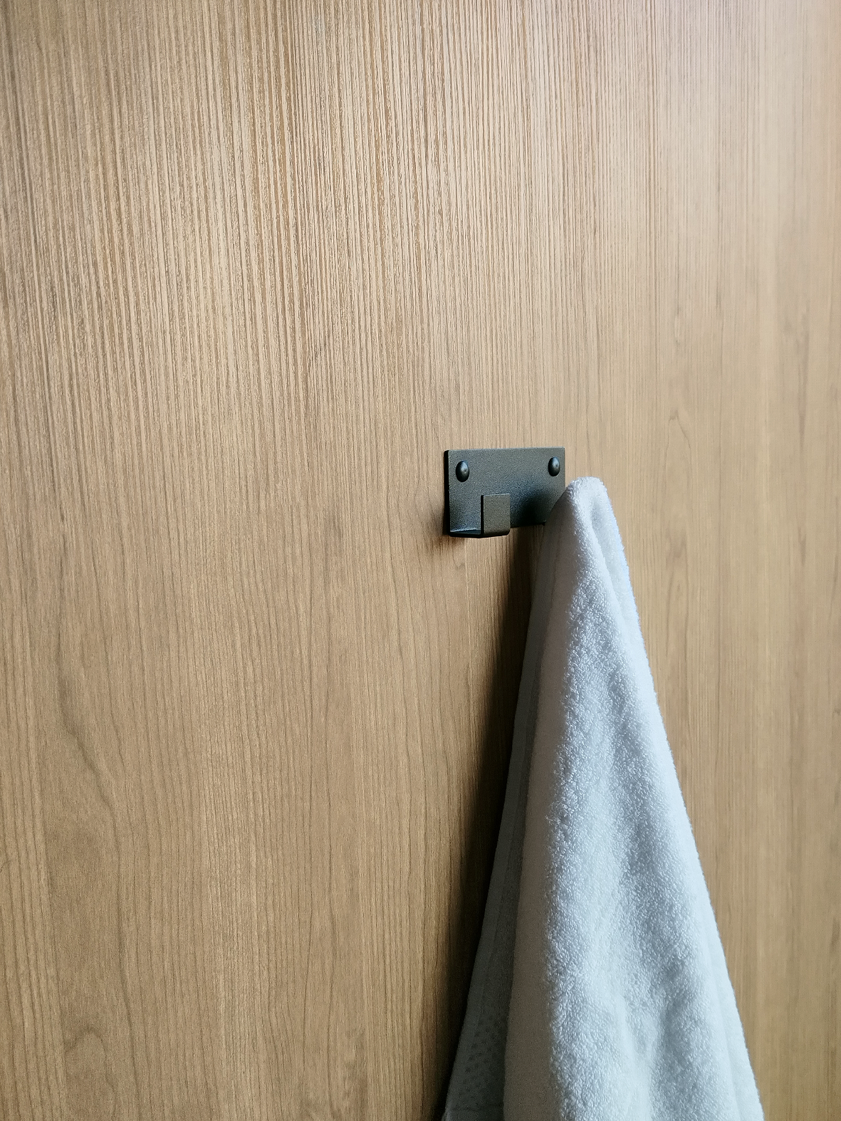 A double black towel hook or wall hook for hanging towels in a bathroom design store in Johannesburg. A white towel is hanging from the black coat hook