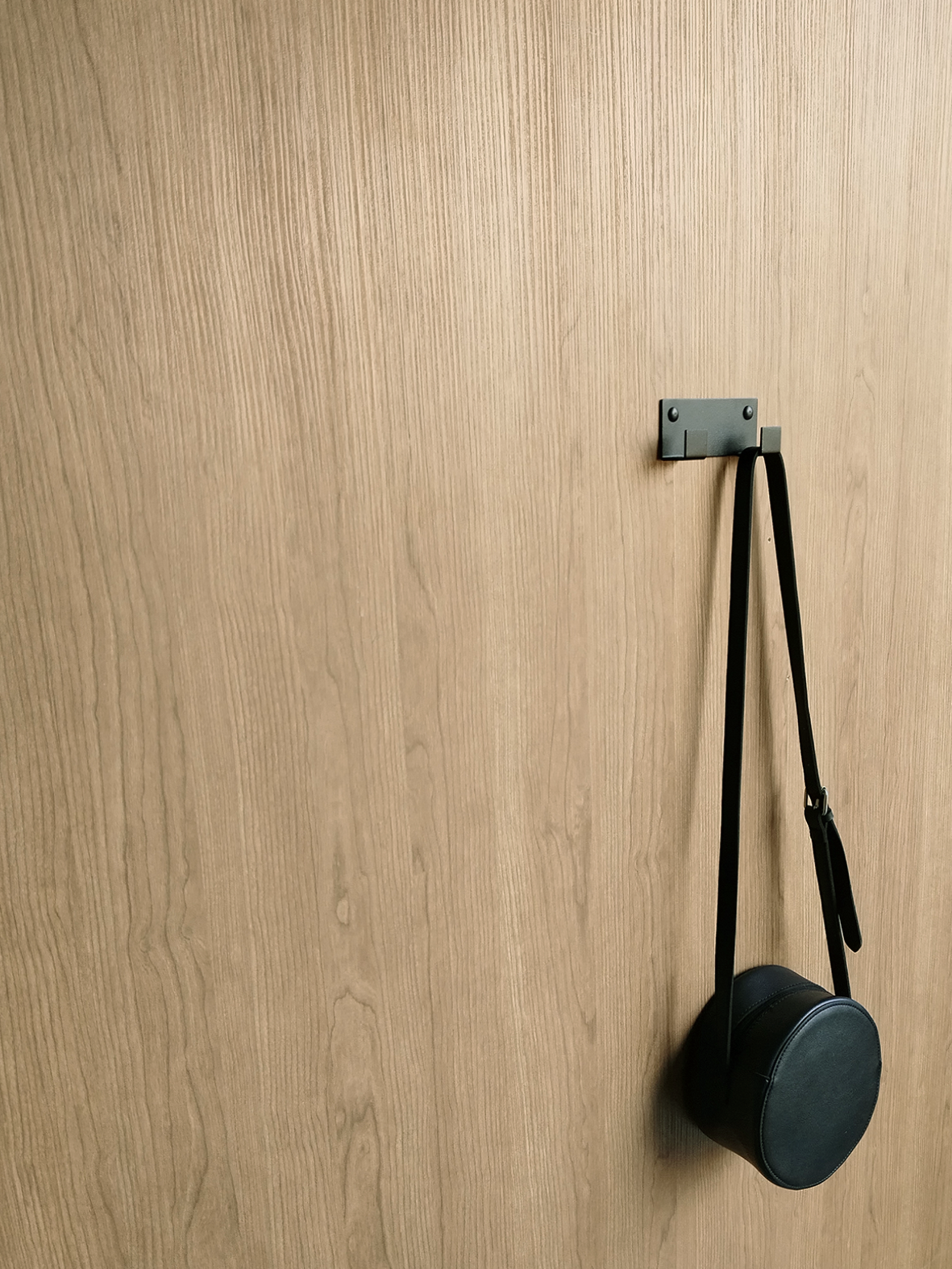 A black coat hook or black wall hook for hanging or a handbag hook is holding a black handbag in a bathroom design store in Joahnnesburg 