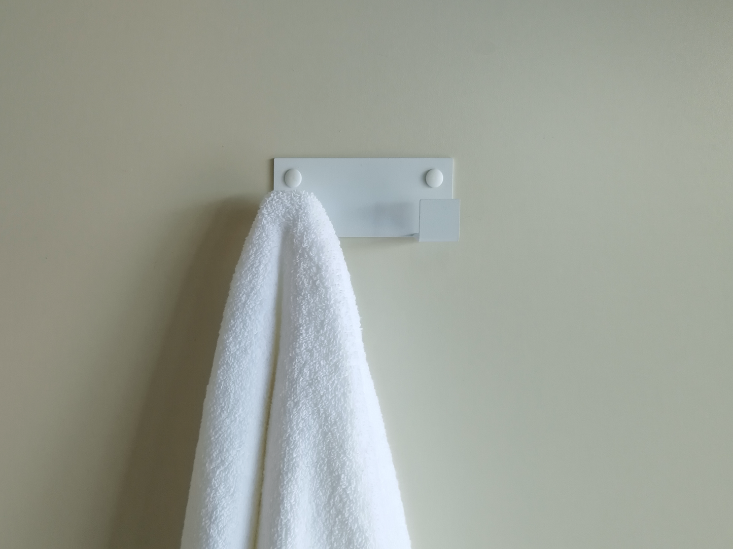 A towel hook in South Africa or a wall hook in South Africa. The wall hook is hanging a white bathrobe