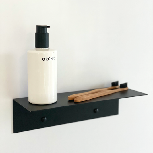 a black steel shelf with a soap dispenser from Mr Price home and bamboo toothbrushes. This bathroom shelf is in a modern bathroom design in johannesburg