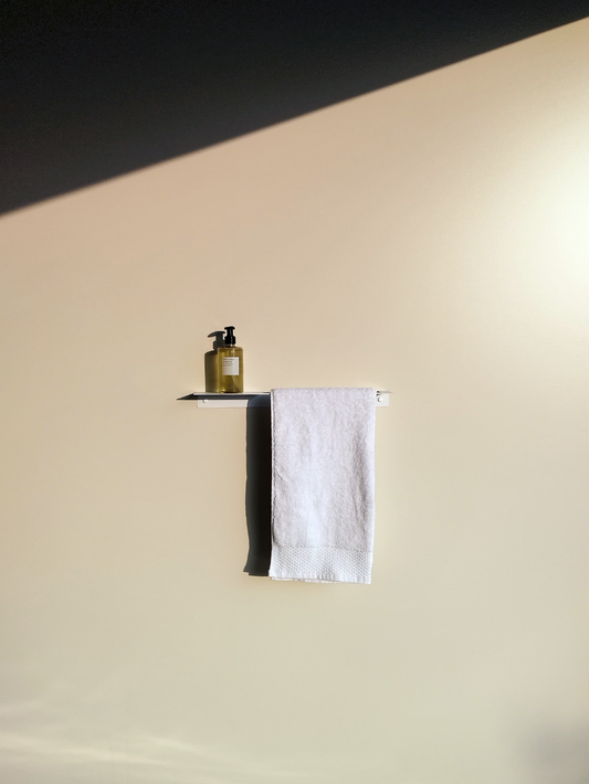 white steel bathroom shelf and towel rail combination product with a soap dispenser from Mr price home and a white towel hanging in a south african bathroom design store in Johannesburg