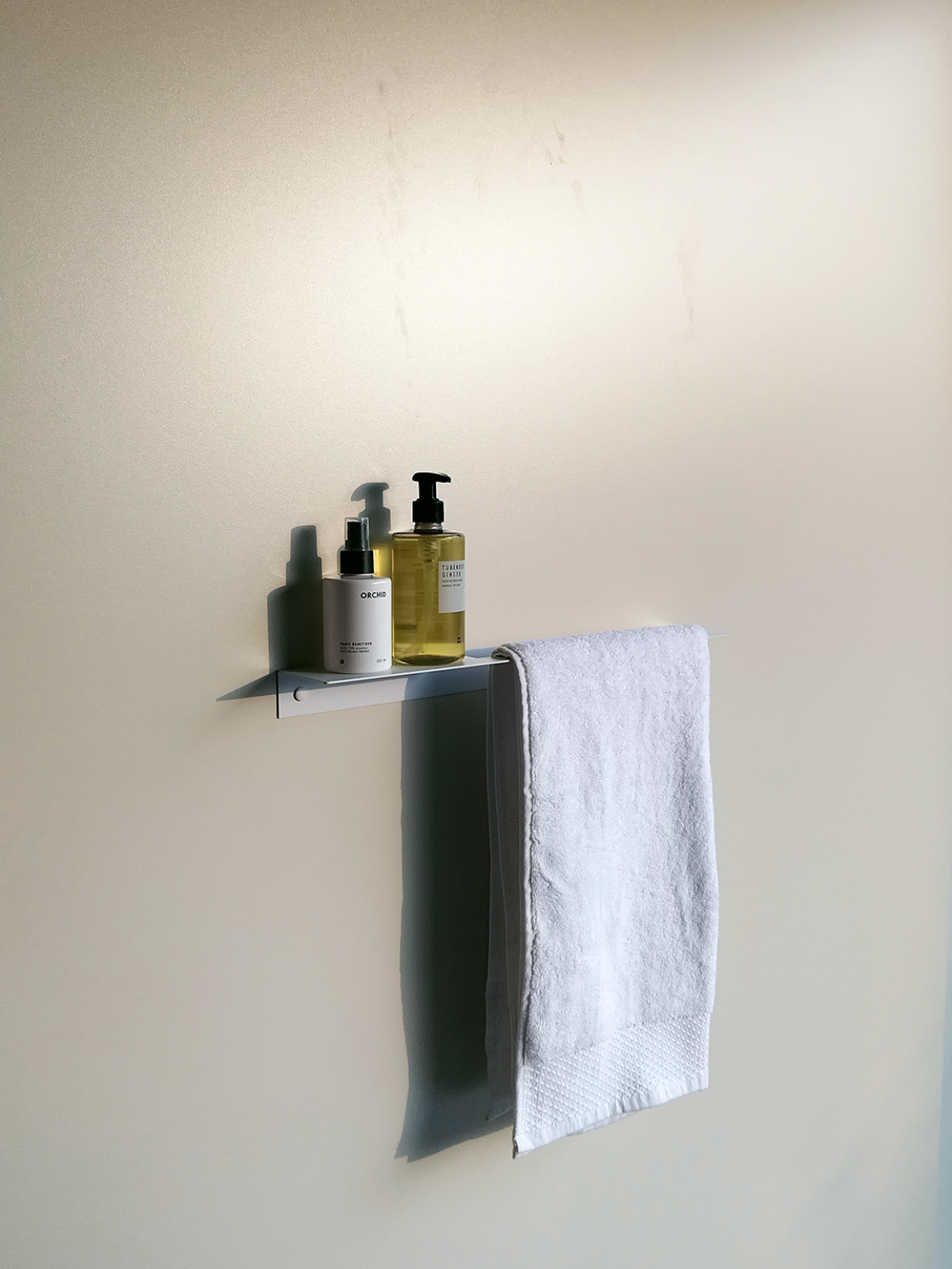 White steel towel shelf or white metal bathroom shelf and white metal towel rail combination product with soap dispensers and towels from Mr Price Home hanging in a South African bathroom design store in Johannesburg